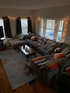 a living room filled with lots of furniture and christmas lights on the windows sill