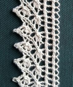 a close up of a piece of white crochet on a green surface with an object in the background