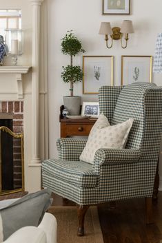 a living room with a chair, fireplace and two pictures on the wall above it