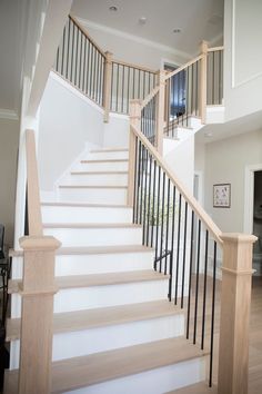 a white staircase with black railing and wood handrails