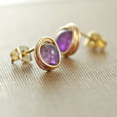 Amethyst gemstone post earrings made with purple amethyst gems wrapped with 14k gold filled wire-- beautiful and understated at the same time. I love how the wrapping gives these earrings a great organic feel. Lovely for every day and easily dressed up or down. These earrings are about 7 mm across and come with traditional 14k gold filled clutch-style earring backs. See more post style earrings here: http://www.etsy.com/shop/aubepine?section_id=6718986 And more jewelry in my shop here: http://au Birthstone Earrings, Earrings Purple, Amethyst Gem, February Birthstone, Birthstone Earring, Purple Stones, February Birth Stone, Style Earrings, Amethyst Gemstone