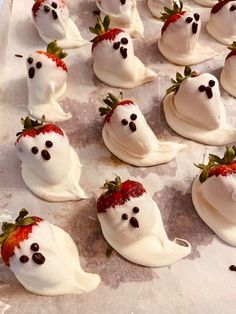 there are many white frosted strawberries in the shape of ghostes with faces on them