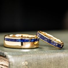 two gold wedding bands with blue lapis inlays on top of an old book