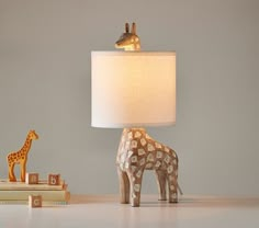 a giraffe lamp sitting on top of a table next to a stack of books