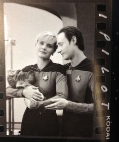 a man and woman in star trek costumes holding a cat, looking at each other