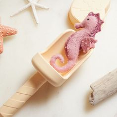 a pink seahorse is in a soap dish next to starfish and seashells