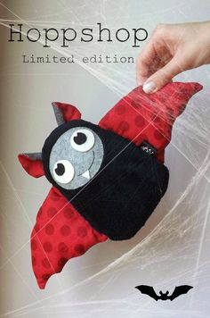 a hand holding a stuffed animal in the shape of a bat with eyes on it