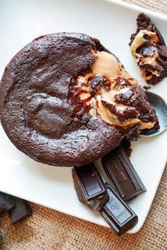 a white plate topped with a chocolate cake and two pieces of ice cream on top of it