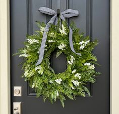 a wreath is hung on the front door with a black and white bow around it