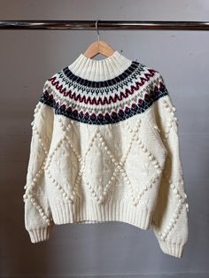 a white sweater hanging on a wooden hanger