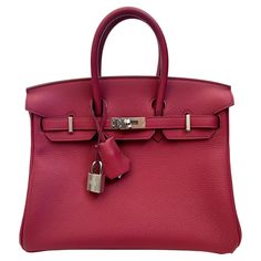 Gorgeous, authentic Hermès 25cm Birkin in Rouge. BRAND NEW, NEVER WORN, and unused condition. Plastic still on the feet/metal pieces throughout. Dark pink togo leather with silver hardware. Features the iconic dual-belt turnstile lock closure. 25cm is the smallest standard Birkin size, with exception to limited edition miniature sizes. Comes with original lock and keys, as well as its original box. Togo leather is a type of calfskin leather with an incredibly soft and fine grain, which is known for its resistance to scuffing. This bag is in perfect condition. 10/10. Comes with its dust cover and box. It is sturdy and functional, yet refined and luxurious. Perfectly clean inside with zero wear. Much of the hardware is still covered with its original plastic. Color is both energetic and matu Luxury Everyday Calf Leather Bag With Lock, Elegant Togo Leather Bag For Business, Formal Calf Leather Bag With Lock, Elegant Togo Leather Business Bag, Formal Togo Leather Bag With Lock, Luxury Calf Leather Bag With Lock, Formal Togo Leather Bags, Luxury Togo Leather Formal Bag, Red Birkin Bag