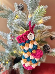 a crocheted ornament hanging from a christmas tree with pine cones in the background