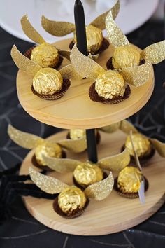 three tiered cake stand with gold foiled chocolates on it and black ribbon