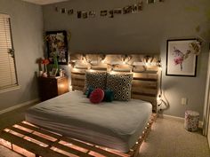 a bed made out of pallets with lights on the headboard and foot board