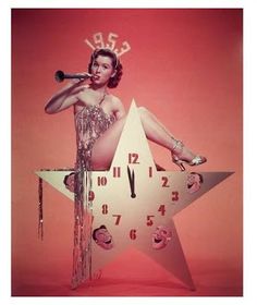 a woman sitting on top of a star with a trumpet in her mouth and clock behind her