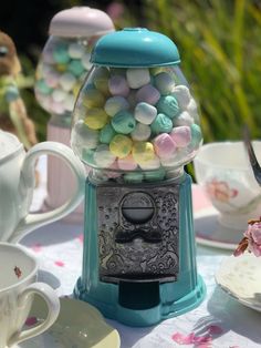 a gummy machine sitting on top of a table next to cups and saucers