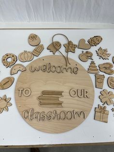 a sign that says welcome to our classroom surrounded by wooden cutouts and other items