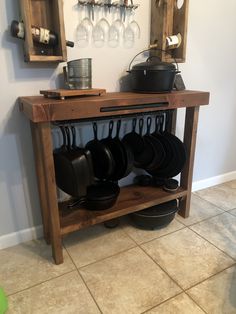 a wooden table with pots and pans on it in a kitchen next to a wall mounted wine rack