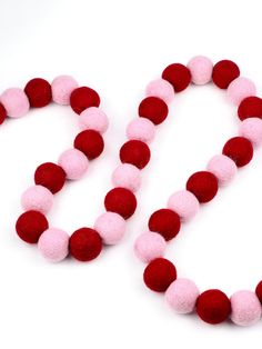 a red and pink beaded necklace on a white background with the word love spelled out