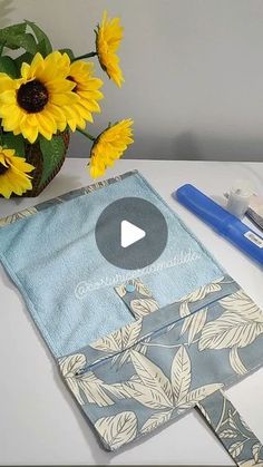 a blue bag sitting on top of a table next to yellow flowers