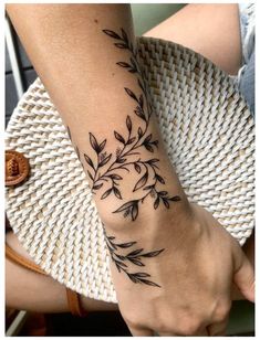 a woman's arm with black leaves on it