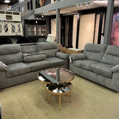 a living room filled with gray couches and chairs next to a coffee table on top of a carpeted floor