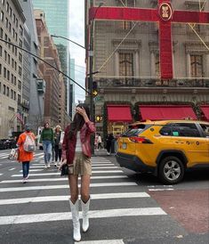 a woman is crossing the street in front of some buildings