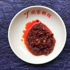 a white bowl filled with sauce on top of a blue table