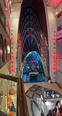 the inside of a building with red lights and pictures on display in front of it