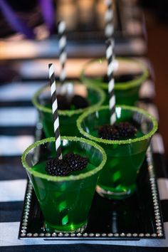 three green cups with blackberries in them on a tray and striped tablecloths