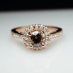 an engagement ring with a brown diamond surrounded by white and gold diamonds on a table