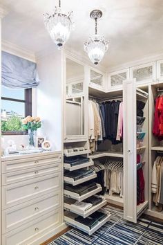 a walk in closet with lots of drawers and clothes hanging on the walls, along with chandeliers