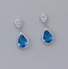 "Layla turquoise blue crystal earrings have the most beautiful sparkle due to the halo of tiny crystals surrounding both the earpost and the teardrop. We have used a clear crystal earpost which is also available as a clip on, to create a versatile and very pretty earring. Measurement: L-1\" (2.5cm) Set in non tarnish rhodium and are nickel, lead and cadmium free. 💙Clip on versions are available for this item. 💞 All our jewelry is presented in velvet pouches and high quality elegant, padded box Blue Crystal Dangle Bridal Earrings, Elegant Blue Crystal Teardrop Earrings, Sapphire Crystal Teardrop Earrings, Blue Crystal Teardrop Bridal Earrings, Blue Crystal Drop Earrings, Blue Drop Crystal Earrings, Blue Crystal Pierced Earrings, Blue Crystal Teardrop Earrings, Blue Crystal Teardrop Dangle Earrings