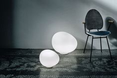 two white lights sitting on top of a floor next to a chair