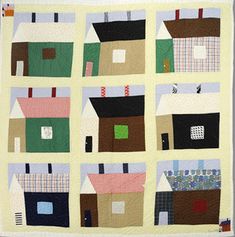 a quilt made to look like houses with different colors and shapes on them, including the roof