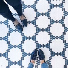 two people standing on a tiled floor with their feet up in front of the camera