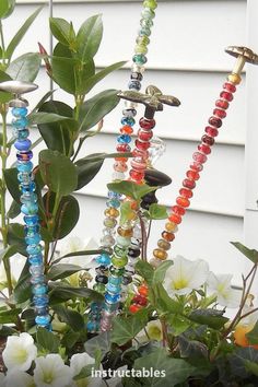 several beads are hanging from a plant in front of a house