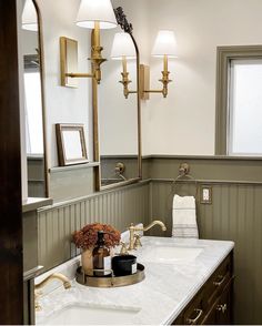 a bathroom with two sinks, mirrors and lights on the wall above them is shown