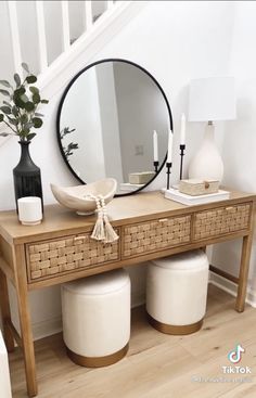 a wooden table with two white stools and a round mirror on top of it