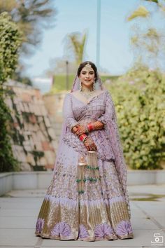 a woman in a purple and gold bridal gown posing for the camera with her hands on her hips