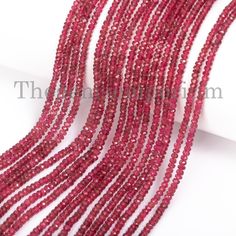 red glass beads are lined up on a white surface