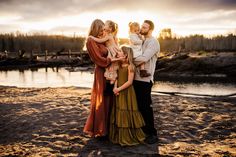 a family standing on the beach at sunset with their arms around each other and looking into the distance