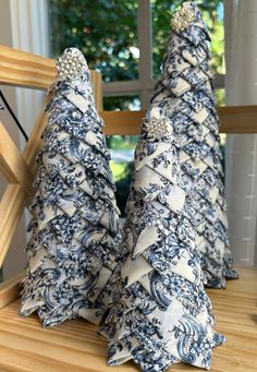 two blue and white christmas trees sitting on top of a wooden table