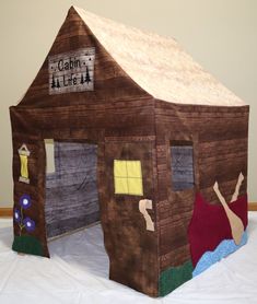 a child's play house made out of wood and cardboard with the door open