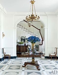 a foyer with chandelier and blue flowers in vases on the coffee table