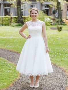 a woman standing in front of a house wearing a white dress