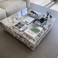 a marble coffee table topped with books and other items