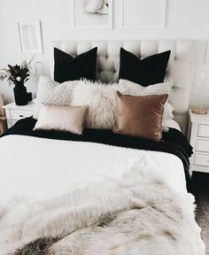 a white bed topped with lots of pillows next to a night stand and nightstands