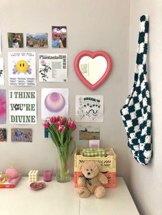 a white table topped with a teddy bear next to a vase filled with flowers