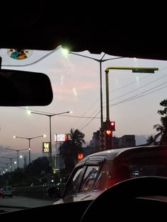 cars are stopped at a red light in the evening time, with palm trees and buildings in the background